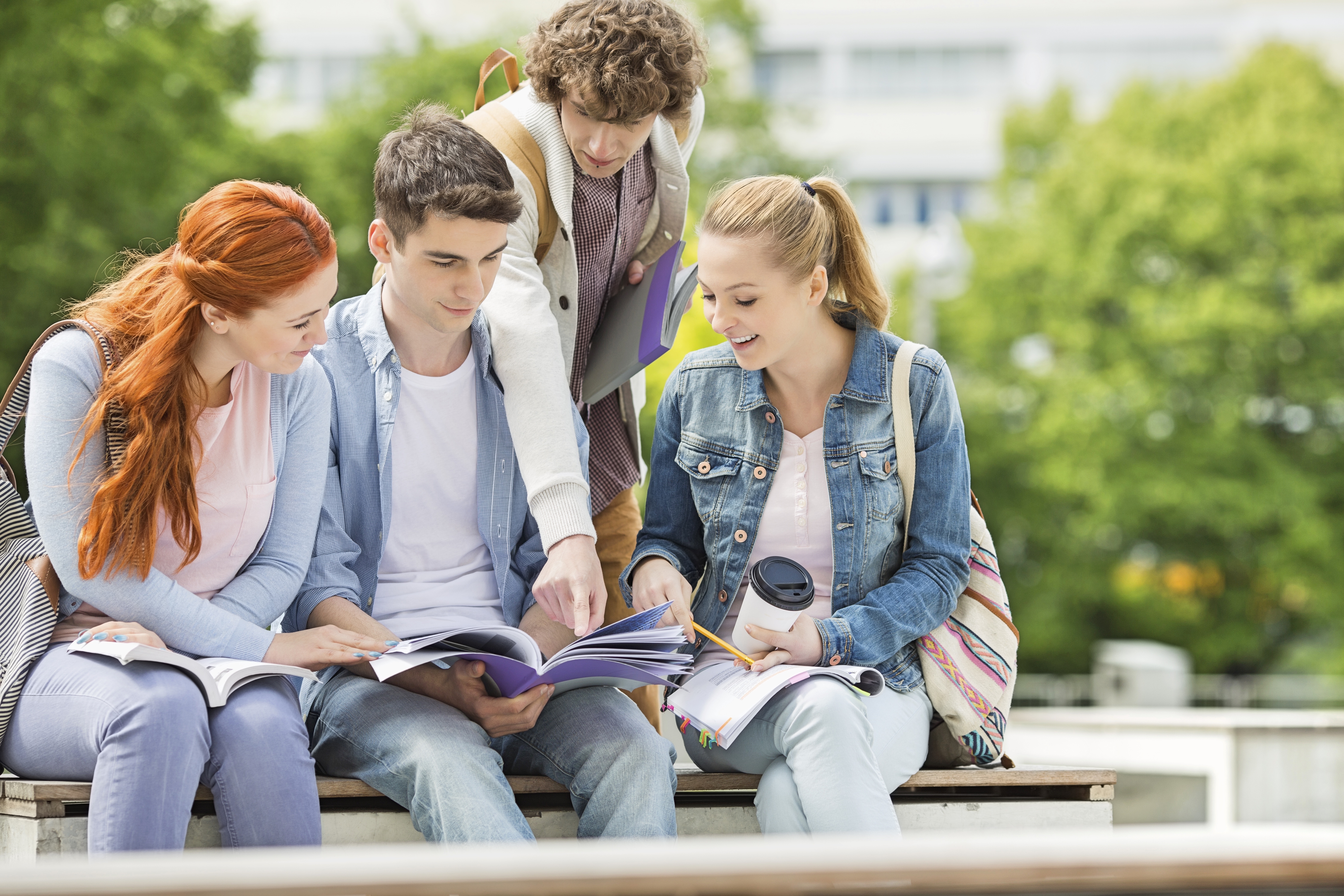 Group of students outdoors on campus studying a document