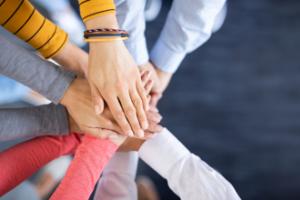 Close up top view of young business people putting their hands together. Stack of hands. Unity and teamwork concept.